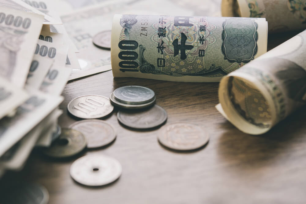 Wibest – Forex Markets: Closeup of Japanese yen money bills and coins on wood table background.