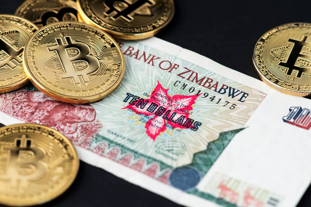 Digital Coins: Bitcoin on Zimbabwe hyperinflation banknote close up.